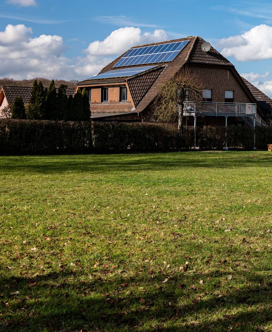 Einfamilienhaus mit Photovoltaikanlage auf dem Dach und grünem Garten
