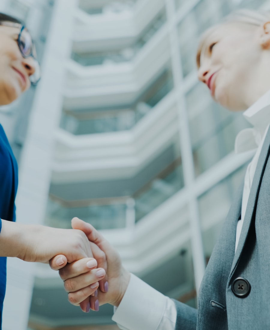 Zwei Geschäftspartner geben sich die Hand in einem modernen Bürogebäude